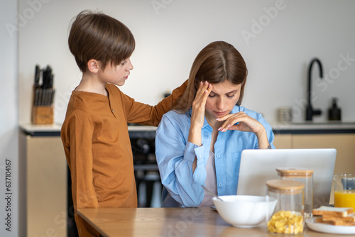 Teenage boy calms down mother. Empathetic sympathetic child strokes frustrated sad tired stressful mom on head, helping to cope with tension. Emotionally close family, warm relationships. photo