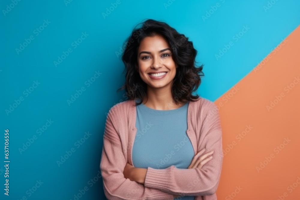 portrait of smiling young woman with crossed arms on blue and orange background portrait of smiling young woman with crossed arms on blue and orange background