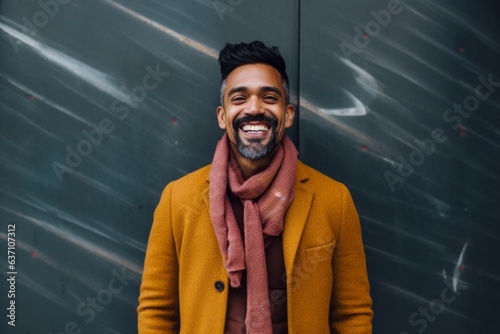 Portrait of a handsome young indian man in coat and scarf smiling