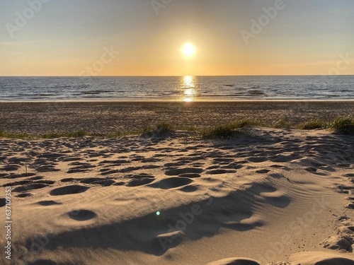 Sunset on the sea with a beach with traces in the sand