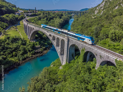 An aerial view of a train crossing the stone railway bridge on the outskirts of the town of Solkan in Slovenia in summertime