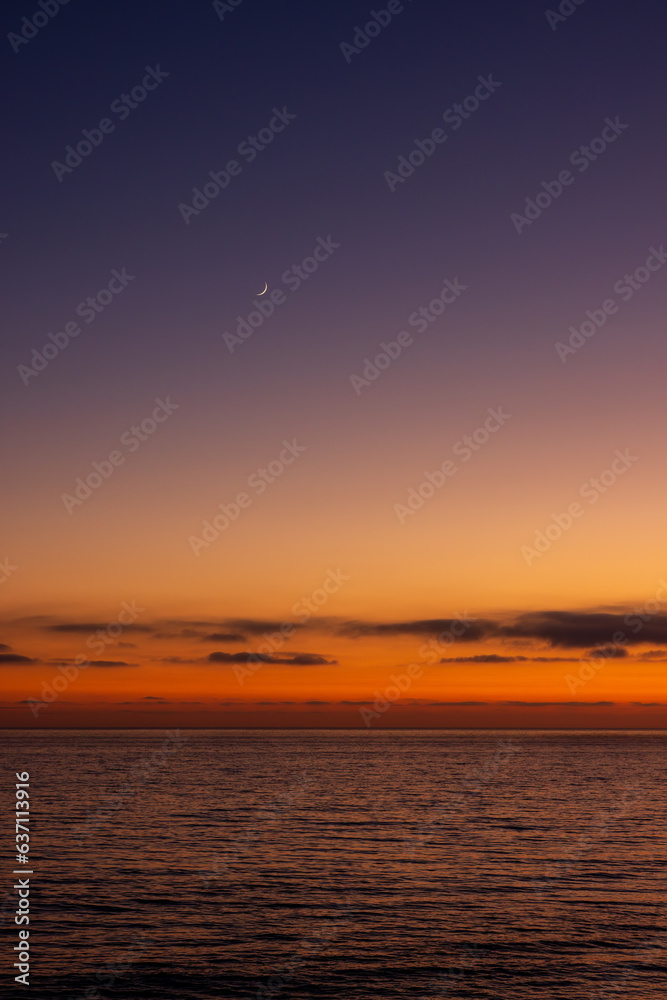 Obraz premium The moon above ocean during sunset