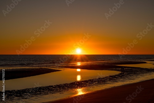 sunset on the beach near the ocean and some sand with water in it