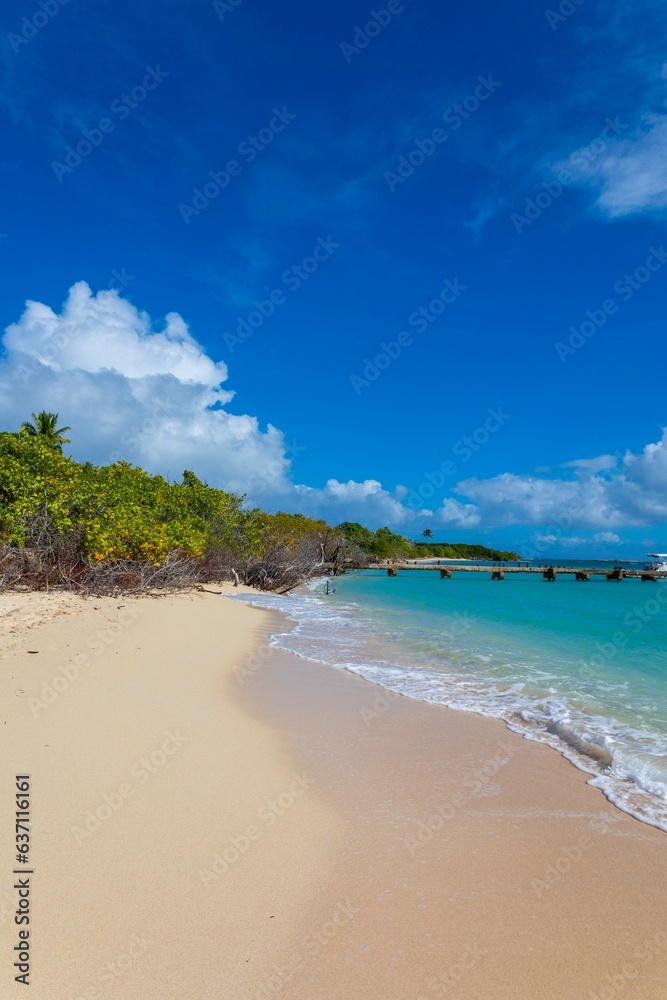 Idyllic beach scene featuring a body of blue and white water surrounded by a clear, bright blue sky Idyllic beach scene featuring a body of blue and white water surrounded by a clear, bright blue sky