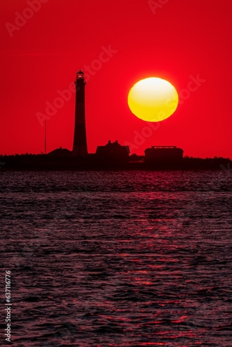 Sun setting behind a lighthouse in the ocean