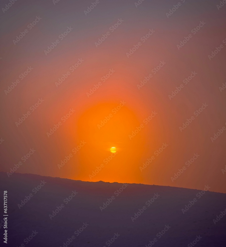 Vibrant orange-yellow sun radiates its light from beyond the horizon