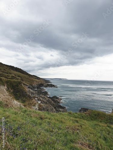Vertical shot of a beautiful sea near the mountains in Rame Head, UK
