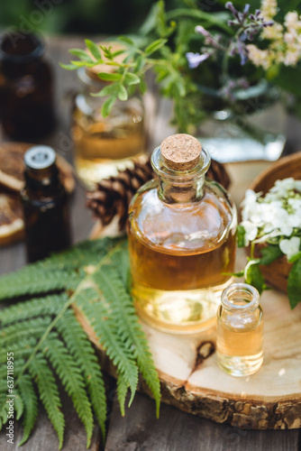 Fototapeta Naklejka Na Ścianę i Meble -  Concept of pure organic essential oil in glass bottles in cosmetology. Moisturising skin care, aromatherapy. Gentle body treatment. Atmosphere of harmony, relax. Wooden background, natural ingredients