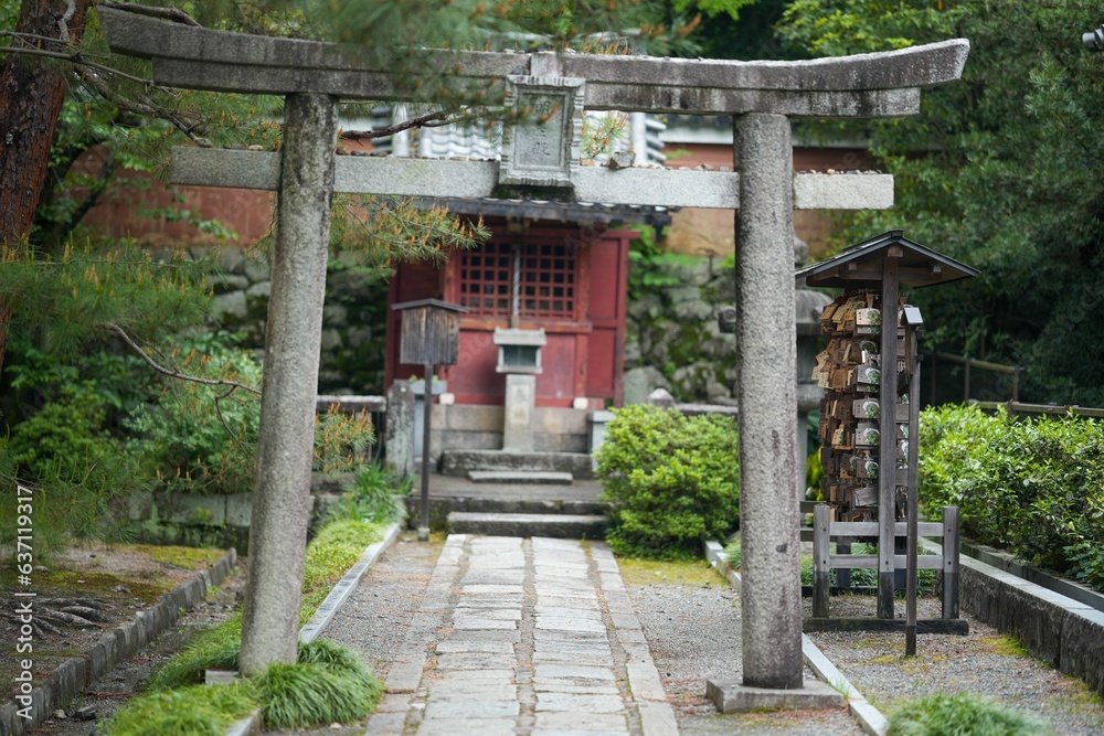 Stone pathway with a stone arch leading to a red building in a park Stone pathway with a stone arch leading to a red building in a park
