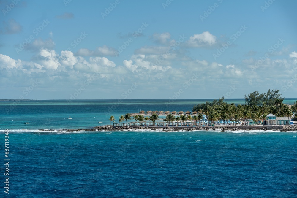 View from the sea of green tropical trees on the shore of tropical island under blue cloudy sky
