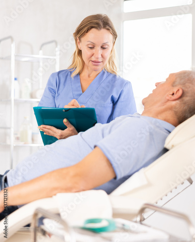 Adult woman medic makes notes in documents in medical room