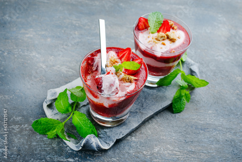 Traditionelle gefrorene Erdbeersuppe mit Erdbeereis und Crumbles serviert als Nahaufnahme auf einem grauen Stein Design Tablett mit Textfreiraum photo