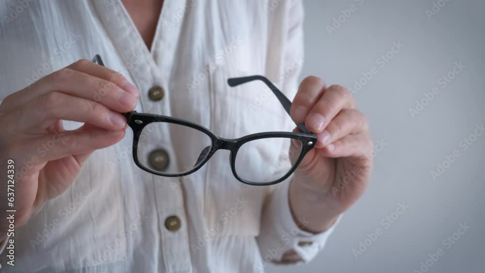 Female eyesight check up with glasses indoor. A woman try to wear her modern eyeglasses in black frame.