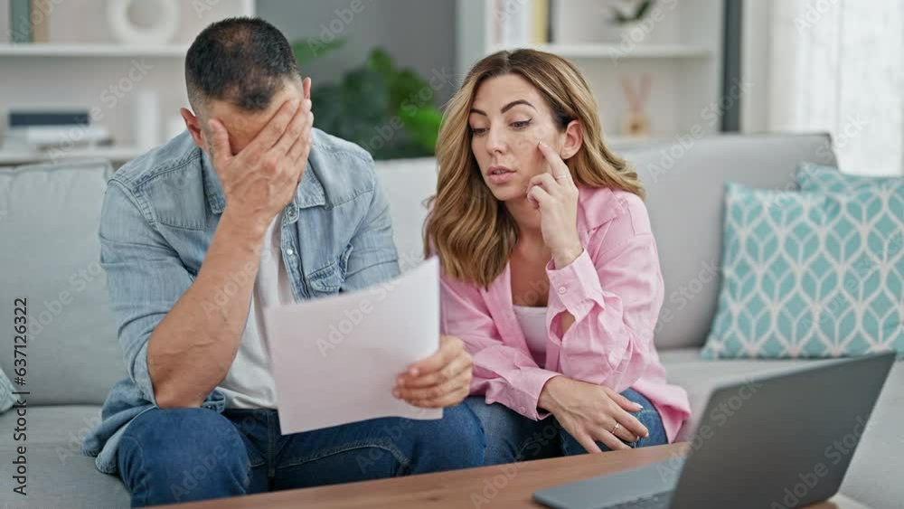 Man and woman couple using laptop reading document at home Man and woman couple using laptop reading document at home