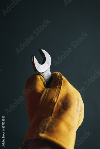 Old worn work glove holding a crescent wrench. Trade work, blue collar worker, or Labor Day concept. photo