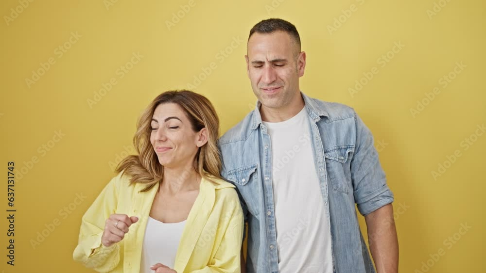 Man and woman couple smiling confident standing together dancing over isolated yellow background Man and woman couple smiling confident standing together dancing over isolated yellow background