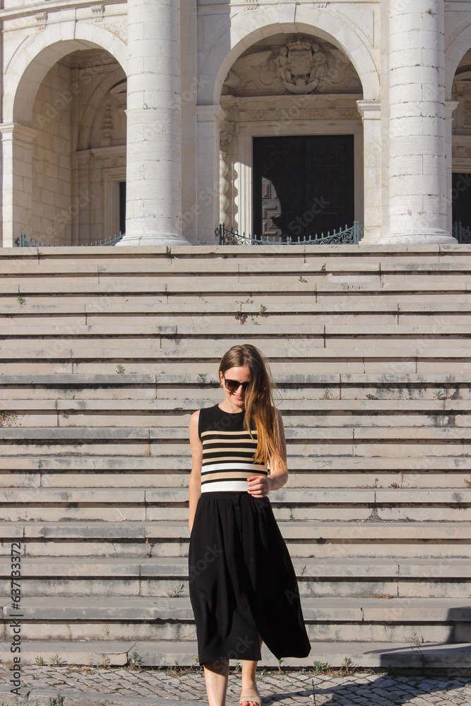 Young adult woman walking up the stairs in front of a huge building. Woman Portrait