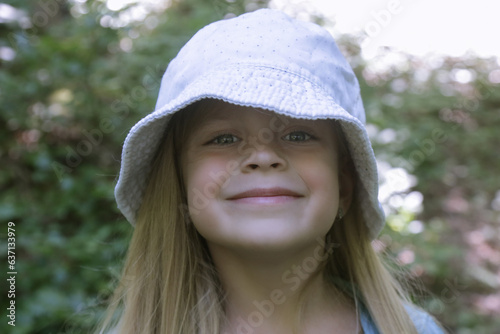 Candid headshot of adorable little girl wearing bucket hat in the forest, spending time in the nature, outdoors experience in the countryside