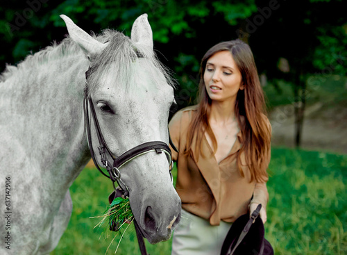 Young girl standing with a grey horse on a grass. Learn horseback riding through lessons. Explore horse therapy, hippotherapy. A woman and her grey horse in a forest, bonding with animals.