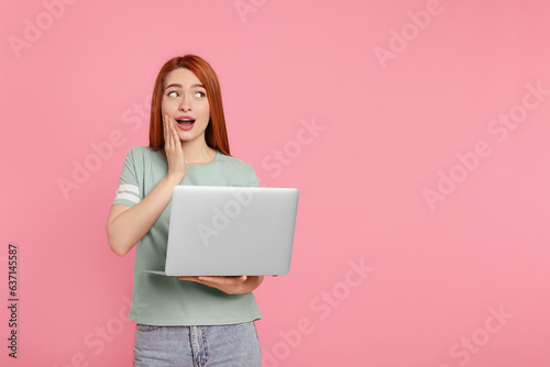 Surprised young woman with laptop on pink background, space for text
