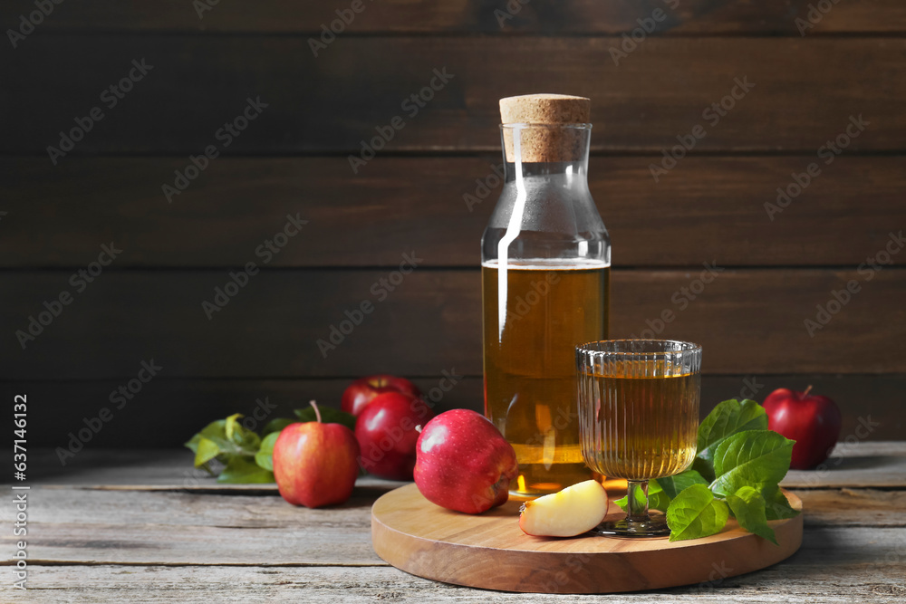 Delicious cider and apples with green leaves on wooden table, space for text Delicious cider and apples with green leaves on wooden table, space for text