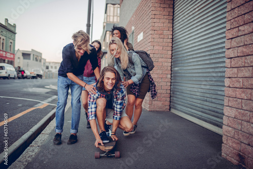 Diverse and young group of people having fun with a skateboard on a city street photo