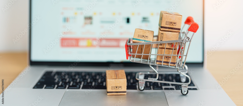 Boxes with shopping cart on a laptop computer. online shopping, Marketplace platform website, technology, ecommerce, shipping delivery, logistics and online payment concepts - obrazy, fototapety, plakaty 