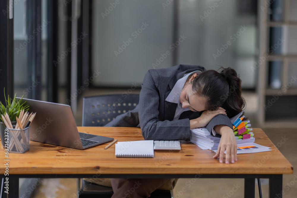 Portrait of tired young business Asian woman work with documents tax laptop computer in office. Sad, unhappy, Worried, Depression, or employee life stress concept Portrait of tired young business Asian woman work with documents tax laptop computer in office. Sad, unhappy, Worried, Depression, or employee life stress concept