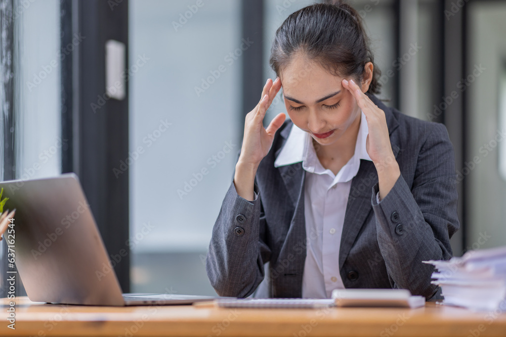 Portrait of tired young business Asian woman work with documents tax laptop computer in office. Sad, unhappy, Worried, Depression, or employee life stress concept Portrait of tired young business Asian woman work with documents tax laptop computer in office. Sad, unhappy, Worried, Depression, or employee life stress concept