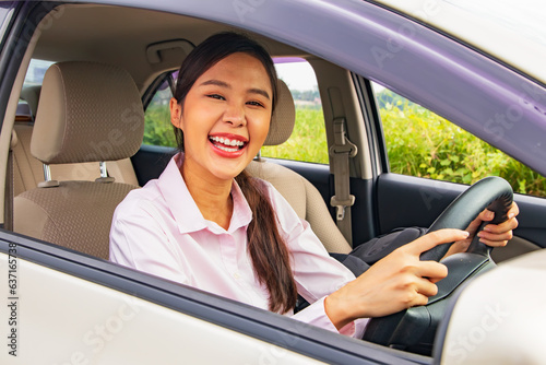 Happy today good day asian businesswoman holding steering wheel on the way looking at the camera as she prepares drive with full confidence drive safely on the road according to the traffic rules.