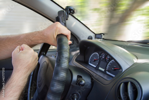 An aggressive driver driving a car exceeds the speed limit. Dangerous aggressive driving. The interior of the car. Men's hands.