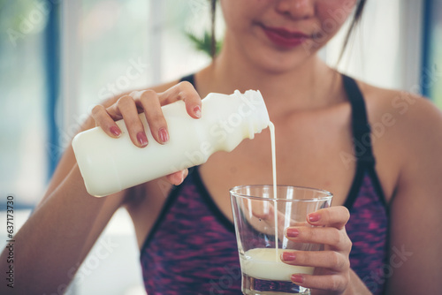Fotografia Women hands holding white glass of milk pouring from bottle