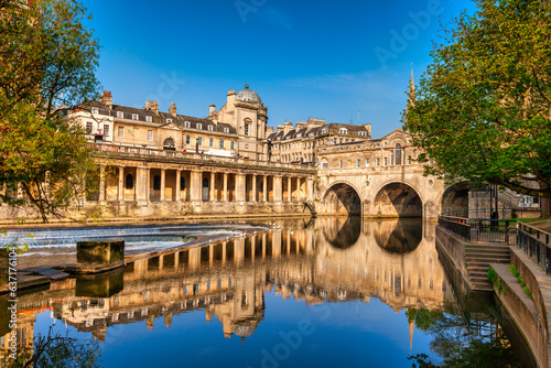 Pulteney Bridge and Weir on the River Avon in the historic city of Bath in Somerset, England, on a bright spring morning with deep blue sky. Stunning reflection, which is genuine.   photo