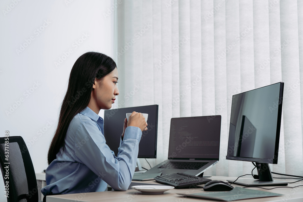 Asian woman was drinking coffee in the early morning while contemplating the program and code on the computer screen. Asian woman was drinking coffee in the early morning while contemplating the program and code on the computer screen.
