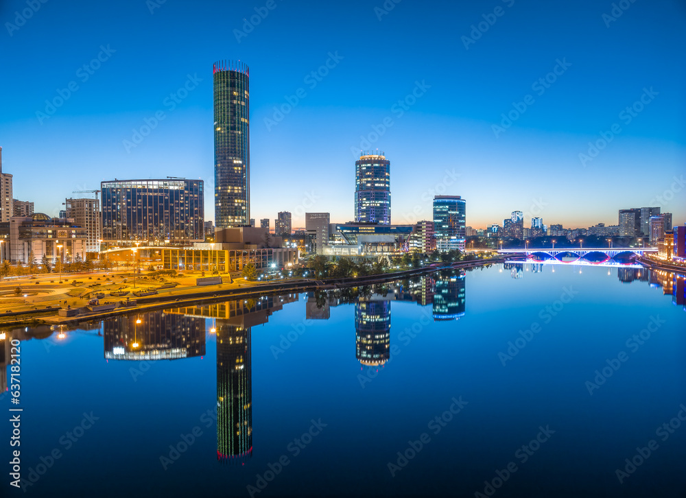 Fototapeta premium Yekaterinburg city and pond aerial panoramic view at summer or early autumn night. Night city in the early autumn or summer.