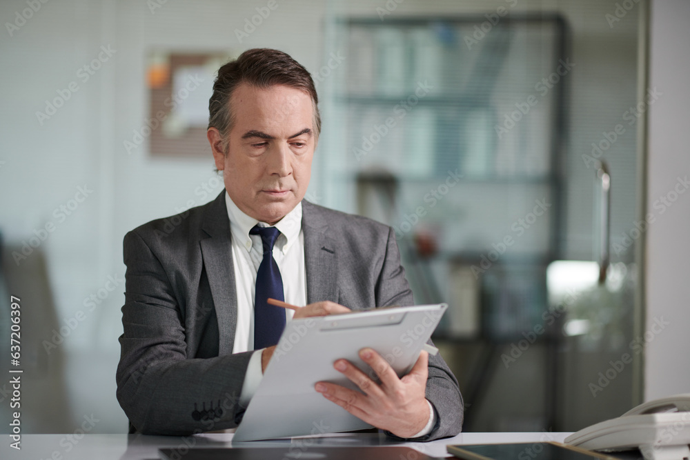 Serious lawyer reading case papers and taking notes Serious lawyer reading case papers and taking notes