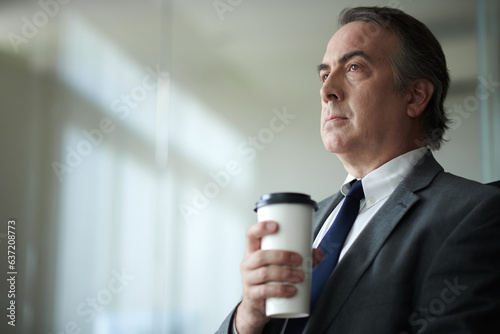 Portrait of serious mature businessman drinking cup of morning coffee