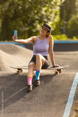 Fototapeta Naklejka Na Ścianę i Meble -  woman skating in a skatepark at sunset making selfie, and calling on the phone