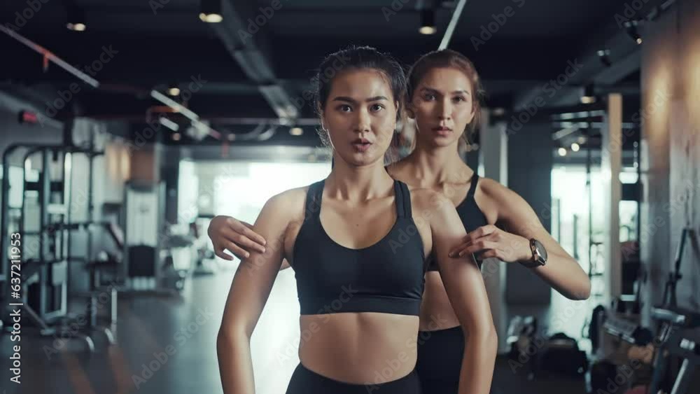 Personal trainer helps her client to work out in the gym and do exercises with dumbbells correctly.
