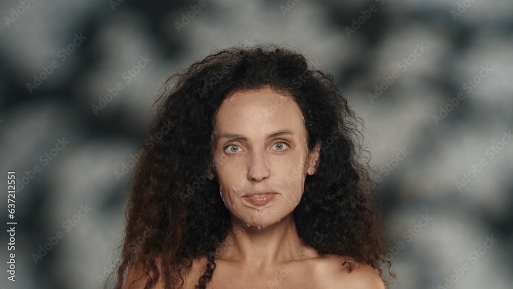Woman in white cosmetic sheet mask on her face. Portrait of a seminude woman in the studio on a black background with highlights. The concept of beauty, cosmetology, care.