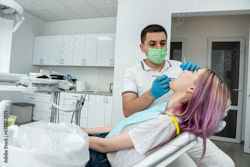 male dentist treats a girl with caries using tools.
