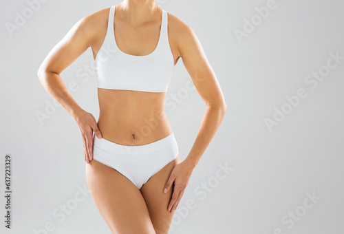 Young and beautiful slender girl in white swimsuit posing over white background. Healthcare, diet, sport and fitness concept.