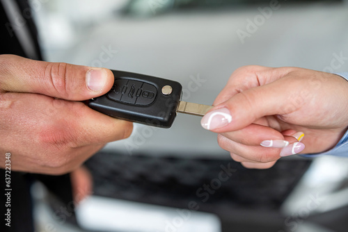 salesman give car key customer after success deal at modern showroom