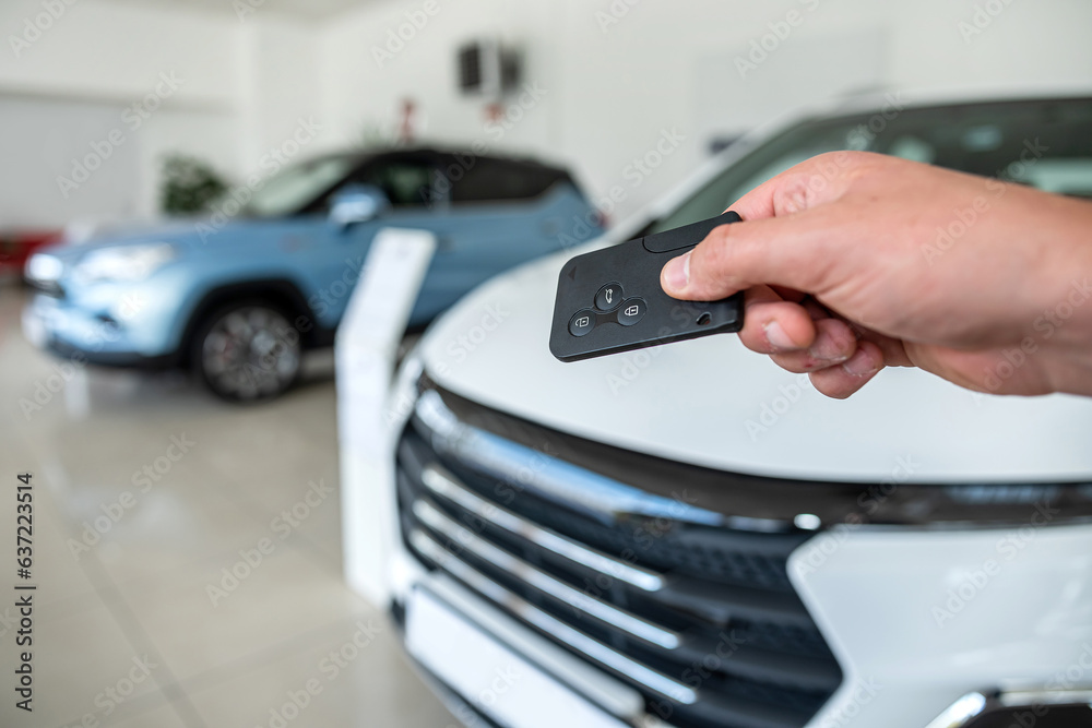 closeup of salesperson holding key against new modern car at showroom closeup of salesperson holding key against new modern car at showroom