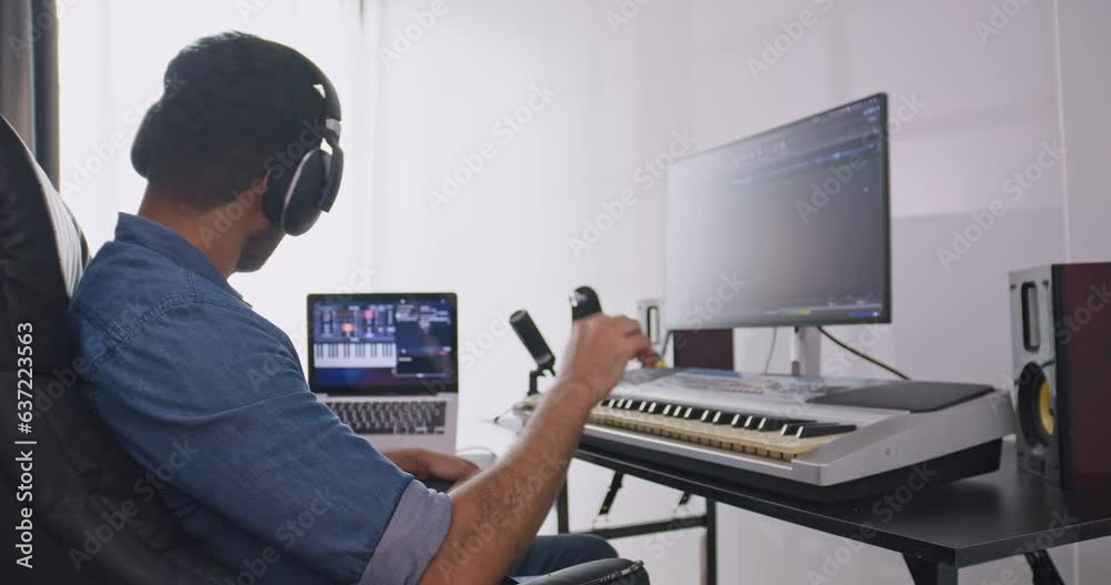 A musician is creating new music in his home studio. A composer is using modern equipment to help create a melody.