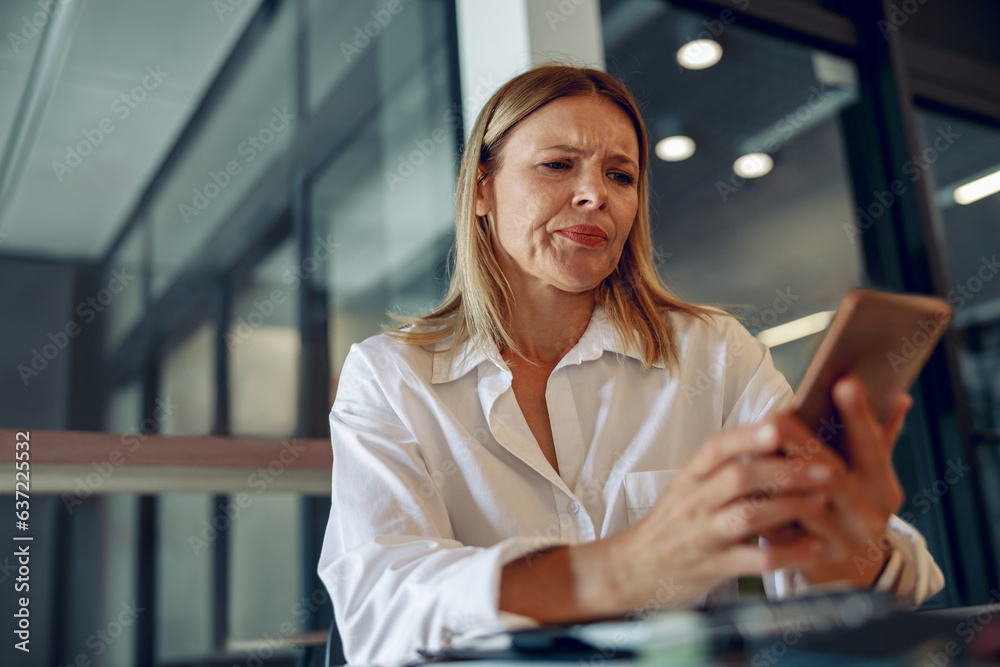 Fototapeta premium Worried woman manager holding phone before calling to client while sitting in office