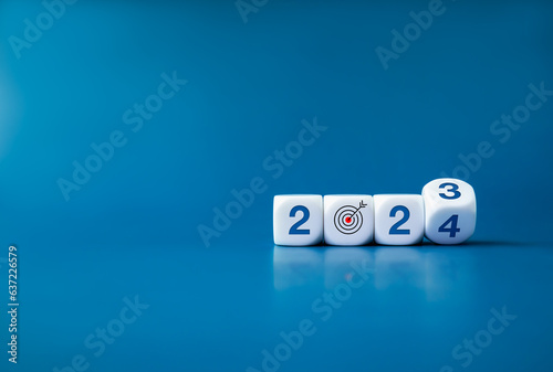 2024 happy new year with the goal and successful concepts. Flipping the 2023 to 2024 year numbers calendar with goal target icon on white cube blocks on dark blue banner background with copy space.