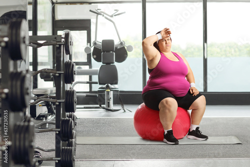 Tired overweight woman sitting on a fintess ball