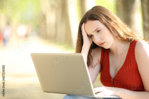 Worried female checking laptop in a park