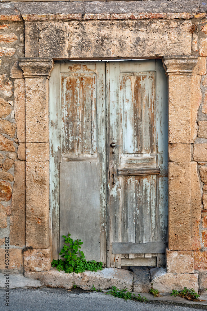 Traditional old wooden door with an elaborated stone built lintel, in the Old Town of Aegina island, in Saronic Gulf near Athens, Greece, Europe. Traditional old wooden door with an elaborated stone built lintel, in the Old Town of Aegina island, in Saronic Gulf near Athens, Greece, Europe.